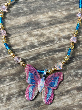 Load image into Gallery viewer, This delicate butterfly pendant is crafted from a basil leaf and adorned with accents of pink, gold and blue. A shining glass beaded necklace crafted from beads of varying shades of pink, gold, and blue, creates a beautiful accompaniment to the butterfly wings. Wear this ravishing necklace and butterfly jewelry pendant to embody the spirit of warm Spring and Summer days. 16 1/4” in length adjustable up to 18"