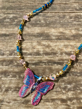 Load image into Gallery viewer, This delicate butterfly pendant is crafted from a basil leaf and adorned with accents of pink, gold and blue. A shining glass beaded necklace crafted from beads of varying shades of pink, gold, and blue, creates a beautiful accompaniment to the butterfly wings. Wear this ravishing necklace and butterfly jewelry pendant to embody the spirit of warm Spring and Summer days. 16 1/4” in length adjustable up to 18"