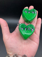 Load image into Gallery viewer, Perfect cute and spooky Halloween item to add to your fridge, locker, cubicle or toolbox. This hand-crafted light and dark green heart-shaped magnet showcases a Frankenstein-inspired design. Measurements: H 1 1/2” x W 1 5/8” x D 1/2”
