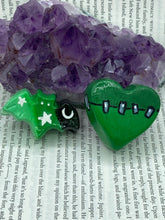 Load image into Gallery viewer, Perfect cute and spooky Halloween item to add to your fridge, locker, cubicle or toolbox. This hand-crafted light and dark green heart-shaped magnet showcases a Frankenstein-inspired design. Bat magnet statuette boasts stunning ombre coloration, transitioning from black to dark green to light green to recreate the breathtaking look of a starry night sky.