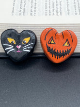 Load image into Gallery viewer, Perfect cute and spooky Halloween magnet art to add to your fridge, locker, cubicle or toolbox. This hand-crafted heart-shaped magnet features a figurine of a black cat with distinctive yellow eyes. Bright orange Jack O Lanterns heart shaped magnet.