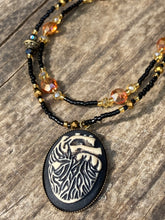 Load image into Gallery viewer, This spooky resin anatomical heart pendant is too cute!!! The pendant is made of resin with brass metal backing. An assortment of floral metal beads to give it a contrast to the soft, dainty style of the glass beaded necklace. Tiny shimmer black glass beads with yellow and orange glass beads to give it a pop of color. Necklace measures 16” adjustable up to 18” in length, pendant is 1 1/4” Height