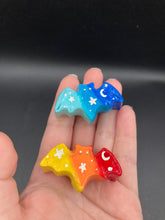 Load image into Gallery viewer, Cute and spooky magnet design to adorn your refrigerator, lockers, workstation, toolbox, or dishwasher. This hand-sculpted clay bat statuette boasts stunning ombre coloration, transitioning from dark blue to light blue and dark red/orange and to light yellow to recreate the breathtaking look of a starry night sky. H 1” x W 2” x D 1/2”