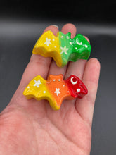 Load image into Gallery viewer, Cute and spooky magnet design to adorn your refrigerator, lockers, workstation, toolbox, or dishwasher. This hand-sculpted clay bat statuette boasts stunning ombre coloration, transitioning from dark red to orange and then to light yellow and to dark green to light green and then to bright yellow to recreate the breathtaking look of a starry night sky. H 1” x W 2” x D 1/2”
