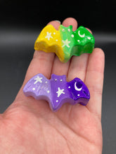 Load image into Gallery viewer, Cute and spooky magnet design to adorn your refrigerator, lockers, workstation, toolbox, or dishwasher. This hand-sculpted clay bat statuette boasts stunning ombre coloration, transitioning from dark green to light yellow and dark purple to light purple to recreate the breathtaking look of a starry night sky. H 1” x W 2” x D 1/2”