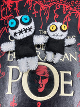 Load image into Gallery viewer, Black and white Voodoo Doll has a black torso, white arms and legs and both round white head with bulging large turquoise buttons, he’s just funny looking. 3 1/2" in height  Super tiny black and white Voodoo Doll has a black torso and white arms, legs and big round white head.  He has bulging yellow button eyes, too big for his tiny head. He looks like he’s almost smiling…almost. He stand at 2 1/2" in height