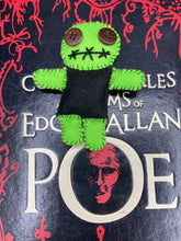 Load image into Gallery viewer, Black And Green Voodoo Doll stand at 3 3/8" in height. Torso is black, while his arms, legs and head is all lime green. He has stylish brown buttons for eyes. Adorable but with a dash of creepy.