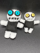 Load image into Gallery viewer, Black and white Voodoo Doll has a black torso, white arms and legs and both round white head with bulging large turquoise buttons, he’s just funny looking. 3 1/2" in height  Super tiny black and white Voodoo Doll has a black torso and white arms, legs and big round white head.  He has bulging yellow button eyes, too big for his tiny head. He looks like he’s almost smiling…almost. He stand at 2 1/2" in height