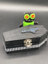 Load image into Gallery viewer, Lime green and black voodoo doll stands at 3" in height. He has a lime green torso but the rest is black. He has a tiny round head with tiny orange buttons for eyes which makes him look cute. His mouth is sowed shut of course so good luck trying to talk to him.