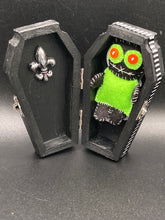 Load image into Gallery viewer, Lime green and black voodoo doll stands at 3" in height. He has a lime green torso but the rest is black. He has a tiny round head with tiny orange buttons for eyes which makes him look cute. His mouth is sowed shut of course so good luck trying to talk to him.