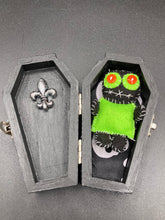 Load image into Gallery viewer, Lime green and black voodoo doll stands at 3" in height. He has a lime green torso but the rest is black. He has a tiny round head with tiny orange buttons for eyes which makes him look cute. His mouth is sowed shut of course so good luck trying to talk to him.