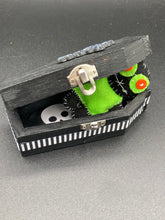 Load image into Gallery viewer, Lime green and black voodoo doll stands at 3" in height. He has a lime green torso but the rest is black. He has a tiny round head with tiny orange buttons for eyes which makes him look cute. His mouth is sowed shut of course so good luck trying to talk to him.