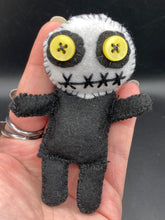 Load image into Gallery viewer, Creepy black and white Voodoo Doll stands tall at 4" in height. He’s all black like a shadow but has a round white head. Bright yellow buttons eyes are perfect to see you better with.
