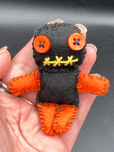 Load image into Gallery viewer, Short and tiny black and orange Voodoo Doll is 3" in height. Torso and head is all black while legs and arms are bright orange, perfect Halloween colors. He has matching bright orange buttons for eyes and has a sowed shut mouth.