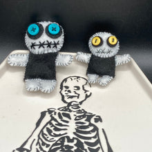 Load image into Gallery viewer, Black and white Voodoo Doll has a black torso, white arms and legs and both round white head with bulging large turquoise buttons, he’s just funny looking. 3 1/2" in height  Super tiny black and white Voodoo Doll has a black torso and white arms, legs and big round white head.  He has bulging yellow button eyes, too big for his tiny head. He looks like he’s almost smiling…almost. He stand at 2 1/2" in height