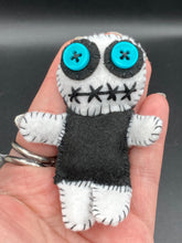 Load image into Gallery viewer, Black and white Voodoo Doll has a black torso, white arms and legs and both round white head with bulging large turquoise buttons, he’s just funny looking. 3 1/2" in height