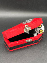 Load image into Gallery viewer, Super tiny black and white Voodoo Doll has a black torso and white arms, legs and big round white head. He has bulging yellow button eyes, too big for his tiny head. He looks like he’s almost smiling…almost. He stand at 2 1/2" in height