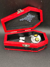 Load image into Gallery viewer, Super tiny black and white Voodoo Doll has a black torso and white arms, legs and big round white head. He has bulging yellow button eyes, too big for his tiny head. He looks like he’s almost smiling…almost. He stand at 2 1/2" in height