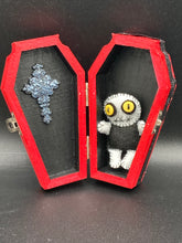 Load image into Gallery viewer, Super tiny black and white Voodoo Doll has a black torso and white arms, legs and big round white head. He has bulging yellow button eyes, too big for his tiny head. He looks like he’s almost smiling…almost. He stand at 2 1/2" in height