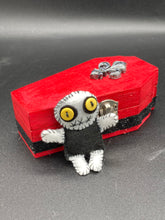 Load image into Gallery viewer, Super tiny black and white Voodoo Doll has a black torso and white arms, legs and big round white head. He has bulging yellow button eyes, too big for his tiny head. He looks like he’s almost smiling…almost. He stand at 2 1/2" in height