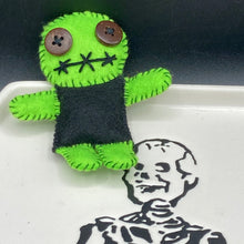 Load image into Gallery viewer, Black And Green Voodoo Doll stand at 3 3/8" in height. Torso is black, while his arms, legs and head is all lime green. He has stylish brown buttons for eyes. Adorable but with a dash of creepy.