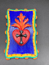 Load image into Gallery viewer, This Sacred Heart Wall Art Decor is the perfect way to enhance your home with an artistic flair. This Sacred Heart Wall Art Decor is crafted with a stunning red heart detailed with a black-silver cross and a vibrant fire embellishment at its center. Adding to its unique traditional Mexican aesthetic, the wood frame is decorated with marigold flowers, creating a beautiful and eye-catching artwork.