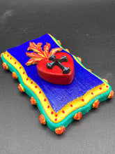 Load image into Gallery viewer, This Sacred Heart Wall Art Decor is the perfect way to enhance your home with an artistic flair. This Sacred Heart Wall Art Decor is crafted with a stunning red heart detailed with a black-silver cross and a vibrant fire embellishment at its center. Adding to its unique traditional Mexican aesthetic, the wood frame is decorated with marigold flowers, creating a beautiful and eye-catching artwork.