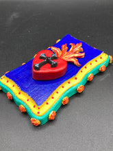 Load image into Gallery viewer, This Sacred Heart Wall Art Decor is the perfect way to enhance your home with an artistic flair. This Sacred Heart Wall Art Decor is crafted with a stunning red heart detailed with a black-silver cross and a vibrant fire embellishment at its center. Adding to its unique traditional Mexican aesthetic, the wood frame is decorated with marigold flowers, creating a beautiful and eye-catching artwork.