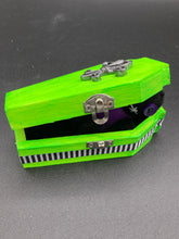 Load image into Gallery viewer, This Lime Green BeetleJuice-inspired Wood Coffin Ring Box is perfect for storing special items. The eye-catching black-silver fleur de lis embellishment and the black and white stripped ribbon gives the box a unique and spooky, yet cute and misfit look. Its all-black interior elevates the aesthetic of this stylish box.