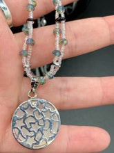 Load image into Gallery viewer, This stylish necklace features a shimmery sterling silver quartz pendant with cats and stars, making it the perfect accessory for any cat lover. With two-hole silver and black beads that stand out against the light aquamarine glass beads, this double strand necklace holds a round kitty pendant made with various hues of clear and iridescent glass beads. Add a touch of purrfection to your look with this statement piece. Measurements: Necklace is 15”adjustable up to 18"