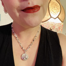 Load image into Gallery viewer, This stylish necklace features a shimmery sterling silver quartz pendant with cats and stars, making it the perfect accessory for any cat lover. With two-hole silver and black beads that stand out against the light aquamarine glass beads, this double strand necklace holds a round kitty pendant made with various hues of clear and iridescent glass beads. Add a touch of purrfection to your look with this statement piece. Measurements: Necklace is 15”adjustable up to 18"