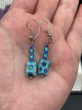 Load image into Gallery viewer, Glass beaded earrings take center stage in this design, with light blue glass beads as the primary color. These beads contain varying shades of blue, purple, and a hint of gold to add interest and texture to the style. As a show-stopping accessory, this piece of jewelry is a must-have for any collection. Measurements: 1 3/8” in length