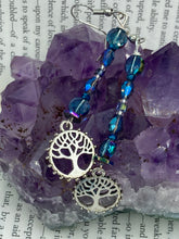 Load image into Gallery viewer, This captivating set of earrings boasts an exquisite range of intense blues and purples, accented with a warm touch of gold and green. The dangling silver plated tree of life charm adds a beautiful finishing touch. Measurements: 2 1/2” in length