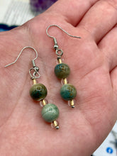 Load image into Gallery viewer, These mossy green round ceramic beads are paired with gold tone glass beads for an earthy and stylish set of earrings. Measurements: 1"