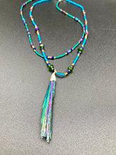 Load image into Gallery viewer, This Celestial and Galaxy Vibe Necklace features a 2 1/2" long Rainbow Kyanite Wired Stone pendant and two strands of multi-color glass beaded necklaces. The glass beads are an eclectic mix of sizes and shapes, including rectangular hematite beads, creating a shimmery, bold display of purples, blues, greens and golds. This necklace truly captures the essence of this celestial galaxy stone.Necklace is 15 1/2” in length can be adjusted to 18" in length