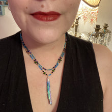 Load image into Gallery viewer, This Celestial and Galaxy Vibe Necklace features a 2 1/2" long Rainbow Kyanite Wired Stone pendant and two strands of multi-color glass beaded necklaces. The glass beads are an eclectic mix of sizes and shapes, including rectangular hematite beads, creating a shimmery, bold display of purples, blues, greens and golds. This necklace truly captures the essence of this celestial galaxy stone.Necklace is 15 1/2” in length can be adjusted to 18" in length