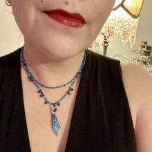 Load image into Gallery viewer, This celestial and galaxy goddess necklace features two strands of glass beading and a captivating Kyanite wired stone pendant. Its mixture of shimmering purples, blues, greens, and golds is truly striking and provides an alluring look like no other. Add this bold and beautiful jewelry piece to your collection today for a statement look that truly stands out. Necklace is 15” in length, can be adjusted to 18"