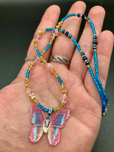 Load image into Gallery viewer, This delicate butterfly pendant is crafted from a basil leaf and adorned with accents of pink, gold and blue. A shining glass beaded necklace crafted from beads of varying shades of pink, gold, and blue, creates a beautiful accompaniment to the butterfly wings. Wear this ravishing necklace and butterfly jewelry pendant to embody the spirit of warm Spring and Summer days. 16 1/4” in length adjustable up to 18"