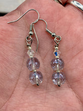 Load image into Gallery viewer, These earrings feature two shimmery iridescent glass beads with a single silver glass bead. Measurements: 1 1/2” in length