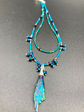 Load image into Gallery viewer, This celestial and galaxy goddess necklace features two strands of glass beading and a captivating Kyanite wired stone pendant. Its mixture of shimmering purples, blues, greens, and golds is truly striking and provides an alluring look like no other. Add this bold and beautiful jewelry piece to your collection today for a statement look that truly stands out. Necklace is 15” in length, can be adjusted to 18"
