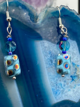 Load image into Gallery viewer, These whimsical earrings feature an eye-catching blend of bright blue glass beads, which feature a blend of blues, purples, and hints of gold. They are further complemented by varying sizes and shapes to create a unique texture and style. This vibrant jewelry is a must-have for any collection. Measurements: 1 ” in length
