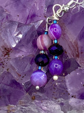 Load image into Gallery viewer, These elegant, glass beaded earrings feature dainty light and dark purple hues, making them a great addition to any summer wardrobe. Perfect for hippie and nature-inspired looks, they are sure to accentuate any style.  Measurements: 1 ” in length