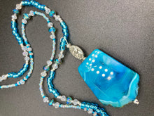 Load image into Gallery viewer, This Vibrant Sea Blue Agate Natural Stone Pendant Choker Style Beaded Necklace includes two strands of glass beads in shades of blues, silver and clear to lend shimmer and color to this large stone pendant. The shorter strand consists of very light blue small glass beads, while the longer strand is primarily a light baby blue. A set of dainty matching earrings completes the look. This beautiful gemstone necklace is the perfect accessory to bring the beach with you in the coming months.