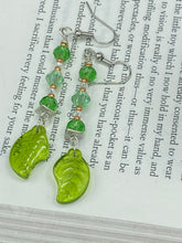 Load image into Gallery viewer, Long strand of glittering light green and gold glass beads, as well as a leaf-shaped glass charm at the bottom, combine to create a highly dynamic effect. These versatile earrings, perfect for a whimsical fairy princess, good witch, or nature-loving hippie look, draw on nature-inspired designs, providing the ideal finishing touch to any ensemble. Measurements: 2 1/4” in length