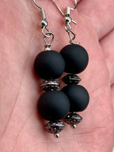 Load image into Gallery viewer, These flat matte black round glass bead earrings with silver plated floral beads offer a versatile look perfect for cocktail chic attire, a wedding necklace, and minimalist style. Measurements: 1 1/4” in length