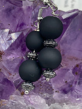 Load image into Gallery viewer, These flat matte black round glass bead earrings with silver plated floral beads offer a versatile look perfect for cocktail chic attire, a wedding necklace, and minimalist style. Measurements: 1 1/4” in length