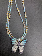 Load image into Gallery viewer, This precious sterling silver pendant features a hand-crafted butterfly whose wings have been artistically molded from a basil leaf and painted in a trio of light blue, silver, and gold hues. Accompanying the butterfly pendant are two glass beaded necklaces in an alluring combination of light blue, gold, and medium-small clear glass beads. A stunning summer accessory.  Measurements:  Necklace is 16” adjustable up to 18" in length