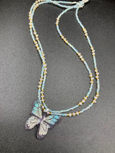 Load image into Gallery viewer, This precious sterling silver pendant features a hand-crafted butterfly whose wings have been artistically molded from a basil leaf and painted in a trio of light blue, silver, and gold hues. Accompanying the butterfly pendant are two glass beaded necklaces in an alluring combination of light blue, gold, and medium-small clear glass beads. A stunning summer accessory.  Measurements:  Necklace is 16” adjustable up to 18" in length