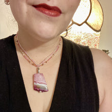 Load image into Gallery viewer, This large agate pendant features a variety of pink hues, from light to dark, and is accompanied by two strands of glass beaded necklaces with pink, silver, gold, and clear beads. The combination of colors creates a stunning and vibrant look, perfect for accessorizing any summer look. Measurements: Necklace is 15” adjustable up to 18" in length