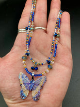Load image into Gallery viewer, This Sterling Silver Dark Blue, Silver and Gold Butterfly Pendant is handcrafted from a basil leaf, and is meticulously painted in brilliant blues and silver. A range of multi-colored glass beads from deep blue to pale silver and gold tones combine to create a stunning lapis stone-like effect. This nature-inspired jewelry piece is perfect for adding a touch of summery style to any look.  Measurements:   Necklace is 15 1/2” adjustable up to 18"